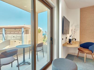Balcone moderno di un hotel con due sedie e un tavolo, vista su un cielo azzurro limpido.