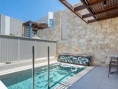 Area piscina moderna con muro in pietra e pergolato di legno in una giornata soleggiata.