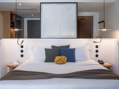 Camera d'hotel moderna con letto grande e dipinto astratto sulla parete.