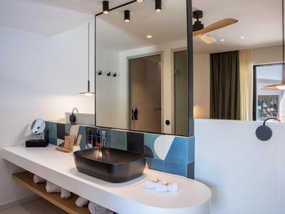 Bagno moderno in hotel con grande piano bianco e lavandino nero.