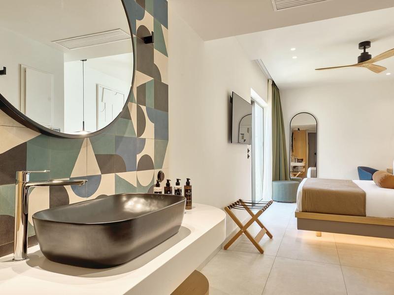 Modern hotel room with open bathroom and stylish black sink.