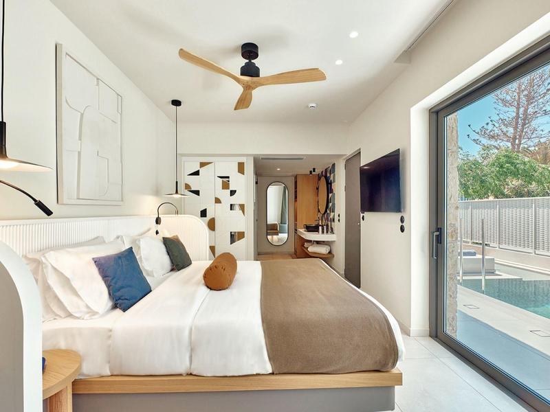 Modern hotel room with large bed, wall art, and view of the pool.