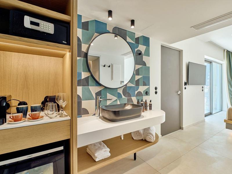 Modern bathroom with round mirror and washbasin in hotel room