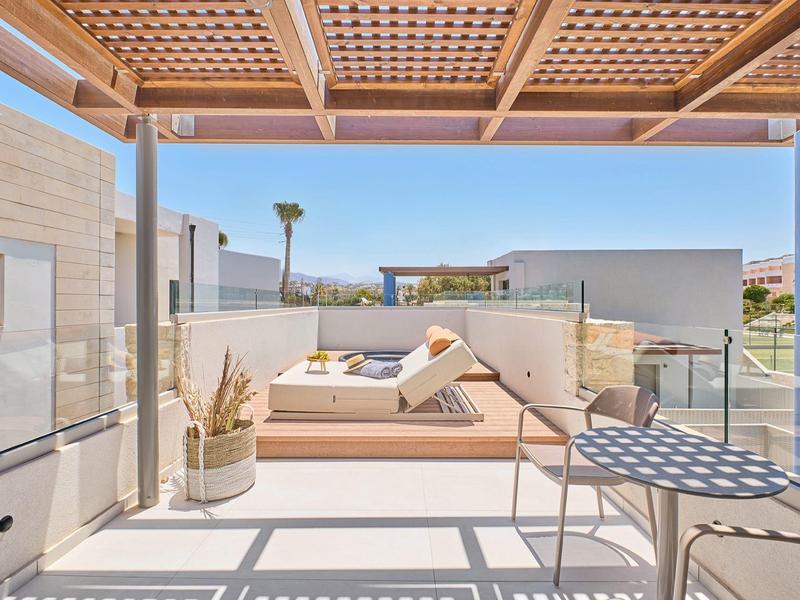 Modern rooftop terrace with lounge chairs, wooden pergola, and views of surrounding buildings.