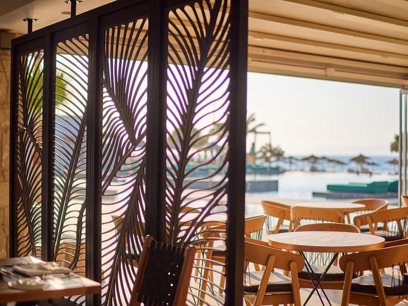 Open dining area with wooden furniture and decorative divider overlooking the sea.