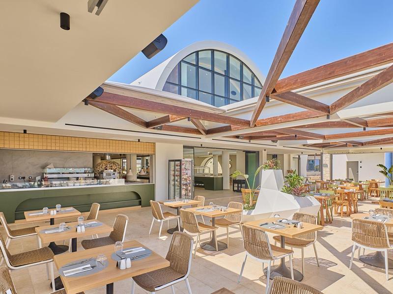 Bright, modern outdoor café area with wooden furniture and pergola roof