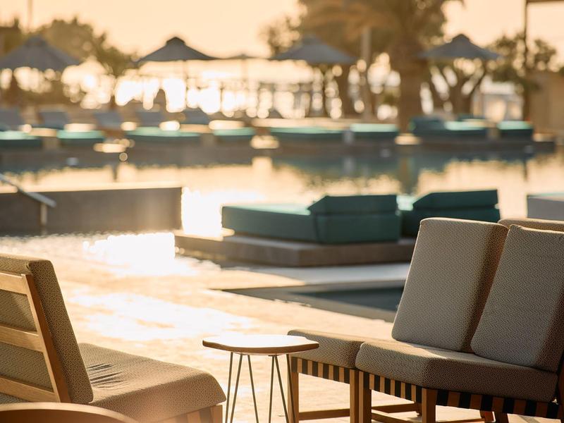 Sunset at hotel pool with loungers and palm trees in the background.