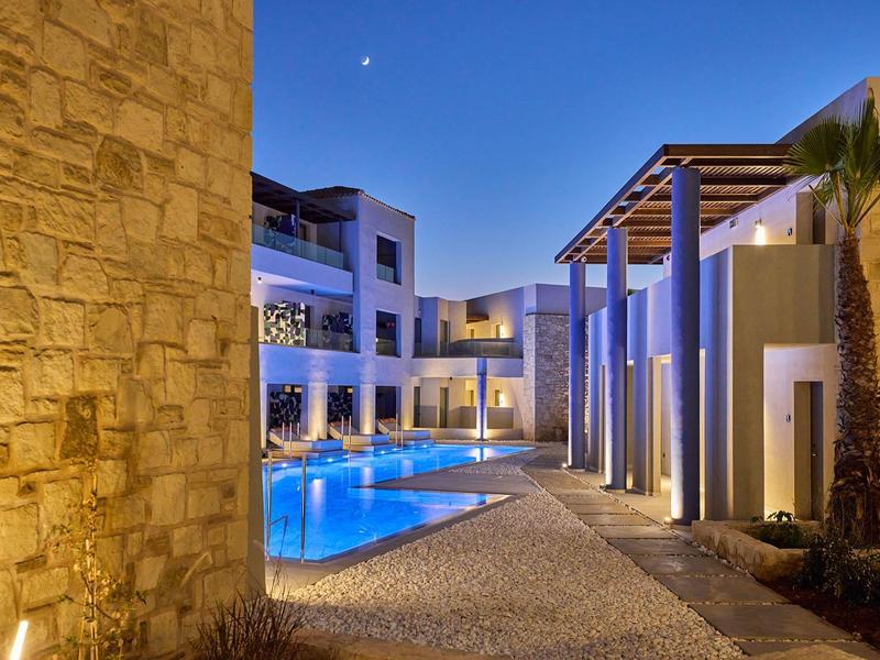 Illuminated hotel with pool and modern architecture at dusk.