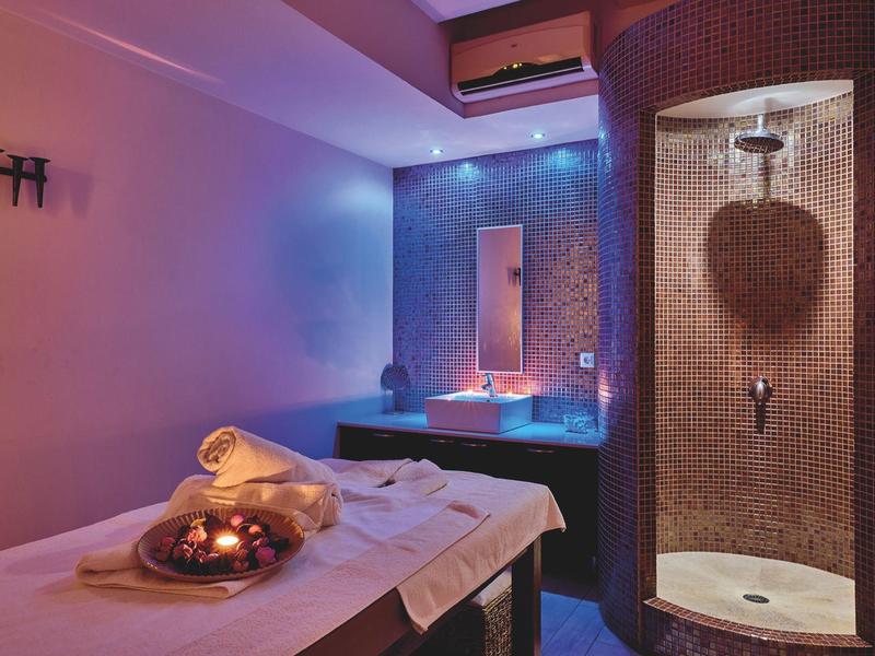 Modern spa room with massage table, shower, and atmospheric lighting.