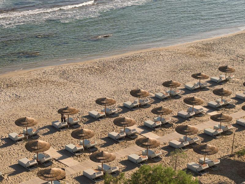 View of a sandy beach with many sun loungers and umbrellas by the sea.