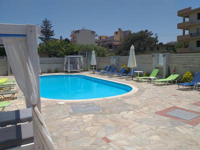 Runder Pool mit Liegestühlen und Sonnenschirmen auf gepflasterter Terrasse im Freien.