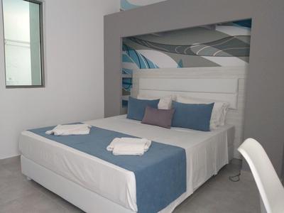 Habitación de hotel moderna con cama doble, cojines azules y manta azul.