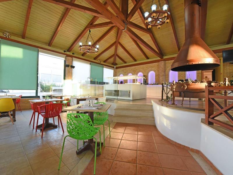 Restaurante luminoso con sillas coloridas y vigas de madera en el techo de un hotel.