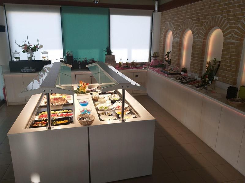 Bufet con diferentes platos en un comedor moderno con paredes de ladrillo y iluminación indirecta.