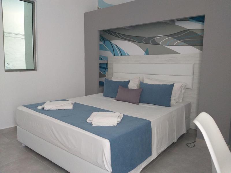 Habitación de hotel moderna con cama doble, cojines azules y manta azul.