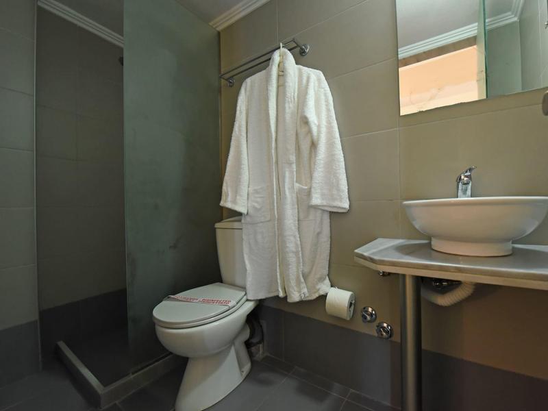 Baño moderno con inodoro, lavabo y bata blanca colgada en la pared.