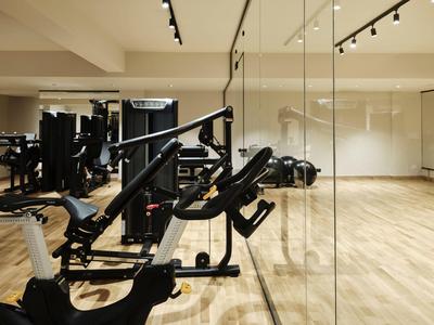 Moderne fitnessruimte met zwarte trainingsapparatuur en lichte houten vloeren in een hotel.