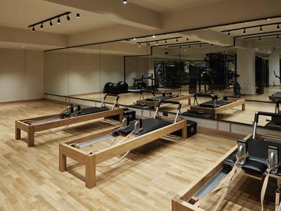 Lichte fitnessruimte met houten vloer en Pilates-apparatuur met spiegelwand.