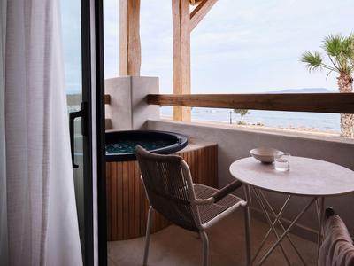 Balkon met hottub, tafel en stoelen met uitzicht op zee op een zonnige dag.