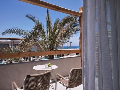Balkon met tafel, twee stoelen, palmbomen en blauwe lucht op een vakantieplek.