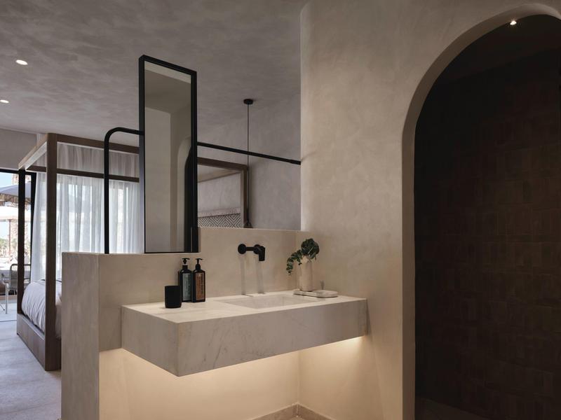 Miroir de salle de bain moderne avec lavabo et éclairage apaisant dans une chambre d'hôtel.