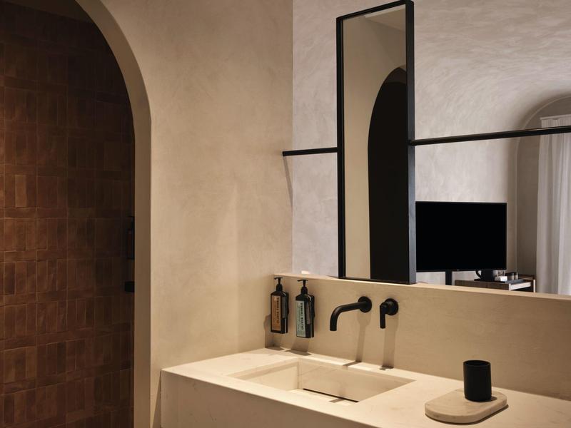 Évier moderne avec robinetterie noire et grand miroir rectangulaire dans une salle de bain lumineuse.