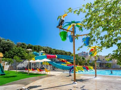 Bunter Wasserspielplatz mit Rutschen, Palmendekor und klarem Himmel im Freibad.