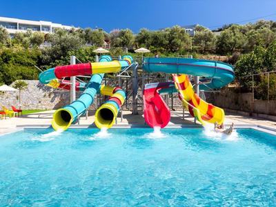 Bunte Wasserrutschen führen in ein klares Schwimmbecken mit blauem Himmel und grünen Bäumen.