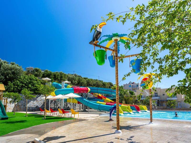 Bunter Wasserspielplatz mit Rutschen, Palmendekor und klarem Himmel im Freibad.