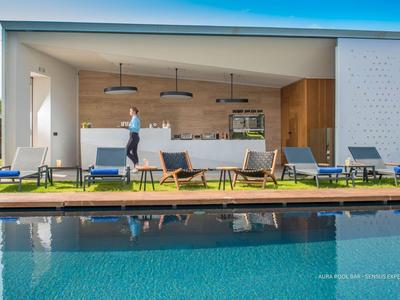 Moderner Außenbereich mit Pool, Loungemöbeln und überdachtem Sitzbereich hinter Glas.