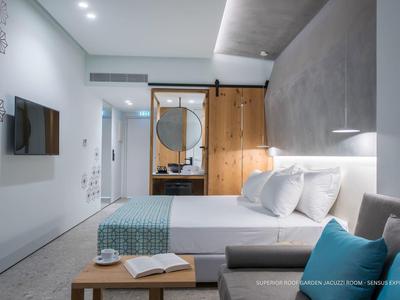 Habitación de hotel moderna con cama doble, puerta corredera de madera, sofá y televisor de pantalla plana.