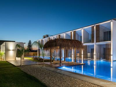 Moderner Hotelpool mit Beleuchtung und Überdachung bei Nacht unter klarem Himmel.