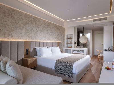 Camera d'hotel moderna con letto matrimoniale, divano, scrivania e illuminazione elegante.