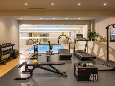 Gimnasio moderno con pesas, kettlebell, cinta de correr y banco de entrenamiento en un hotel.