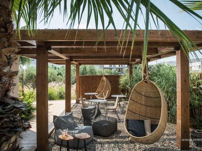 Gemütlicher Außenbereich mit Hängestühlen und Sitzgelegenheiten unter einer Pergola im Hotelgarten.