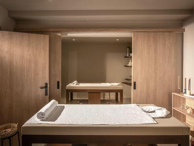 Stanza spa luminosa con lettini per massaggi e mobili in legno dal design caldo.
