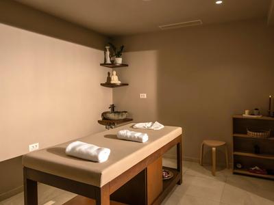 Una stanza per massaggi tranquilla con un lettino e asciugamani in tonalità neutre.