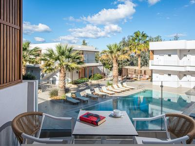 Vista su un'area piscina con lettini e palme in un hotel moderno.