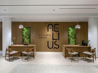 Moderne hotel lobby receptie met houten fronten, groene planten en minimalistische zitgedeeltes.