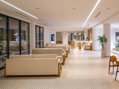 Hall dell'hotel moderno con divani chiari e piante decorative.