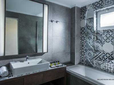 Baño moderno con gran espejo, bañera y azulejos decorativos en la pared.