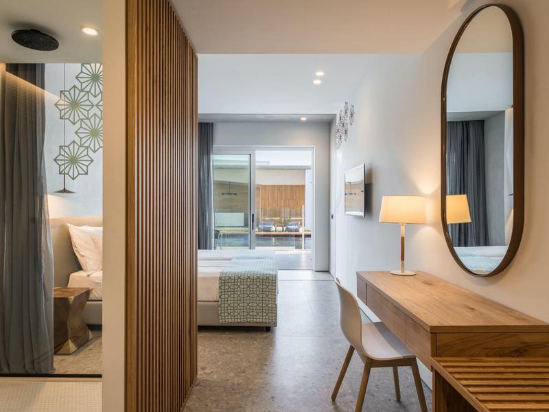 Habitación de hotel moderna con paneles de madera, espejo grande y vista al balcón.