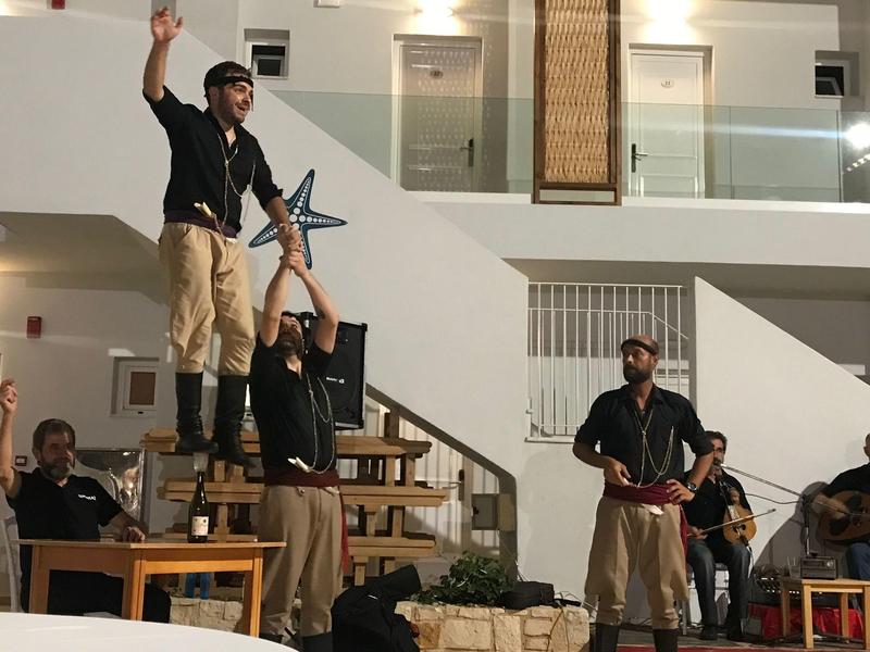 Tres hombres realizan una actuación acrobática en una escalera dentro de un espacio interior.