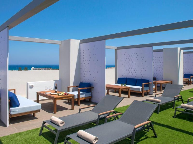 Area spiaggia con sdraio e angoli salotto coperti con vista sul mare.