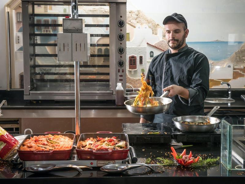Cocinero preparando comida fresca en una cocina profesional con pizza y pimientos.