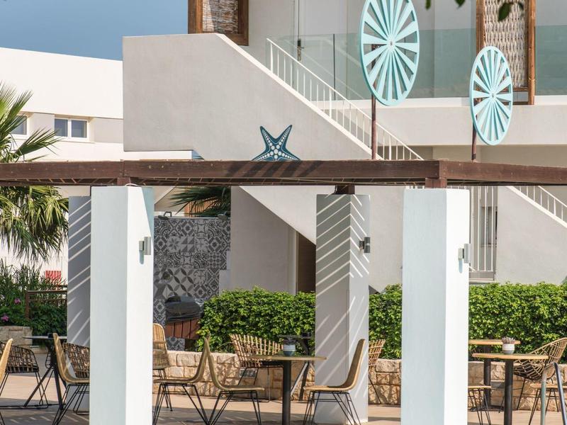 Piscina exterior moderna con columnas blancas y área de descanso en un hotel.