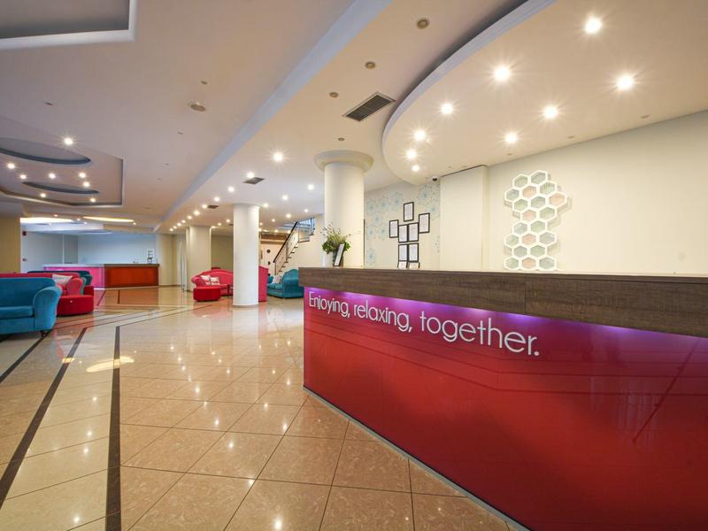 Moderna recepción de hotel con mostrador brillante, suelo pulido y áreas de descanso confortables.