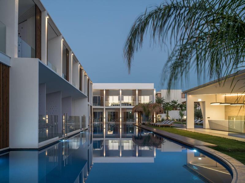 Piscina de hotel moderna al anochecer con diseño minimalista y edificios iluminados.