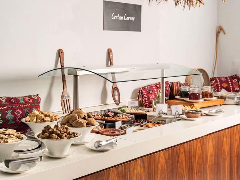 Buffet con varios platos y recipientes sobre una encimera de madera bajo una cubierta de vidrio.