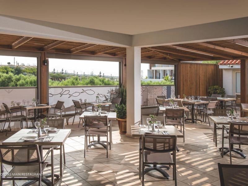 Terraza exterior cubierta con varias mesas y sillas en un restaurante de hotel.